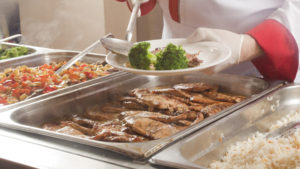 cook placing green broccoli on a pate 